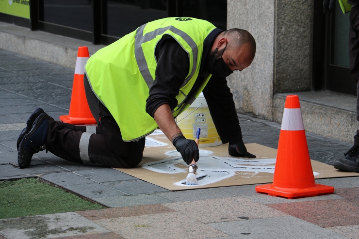 Un treballador pinta la senyalització ideada pel comú d'Escaldes per evitar contagis de Covid-19.
 